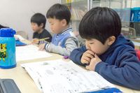 Asian boy students, reading and studying in elementary school classroom. (horiz)