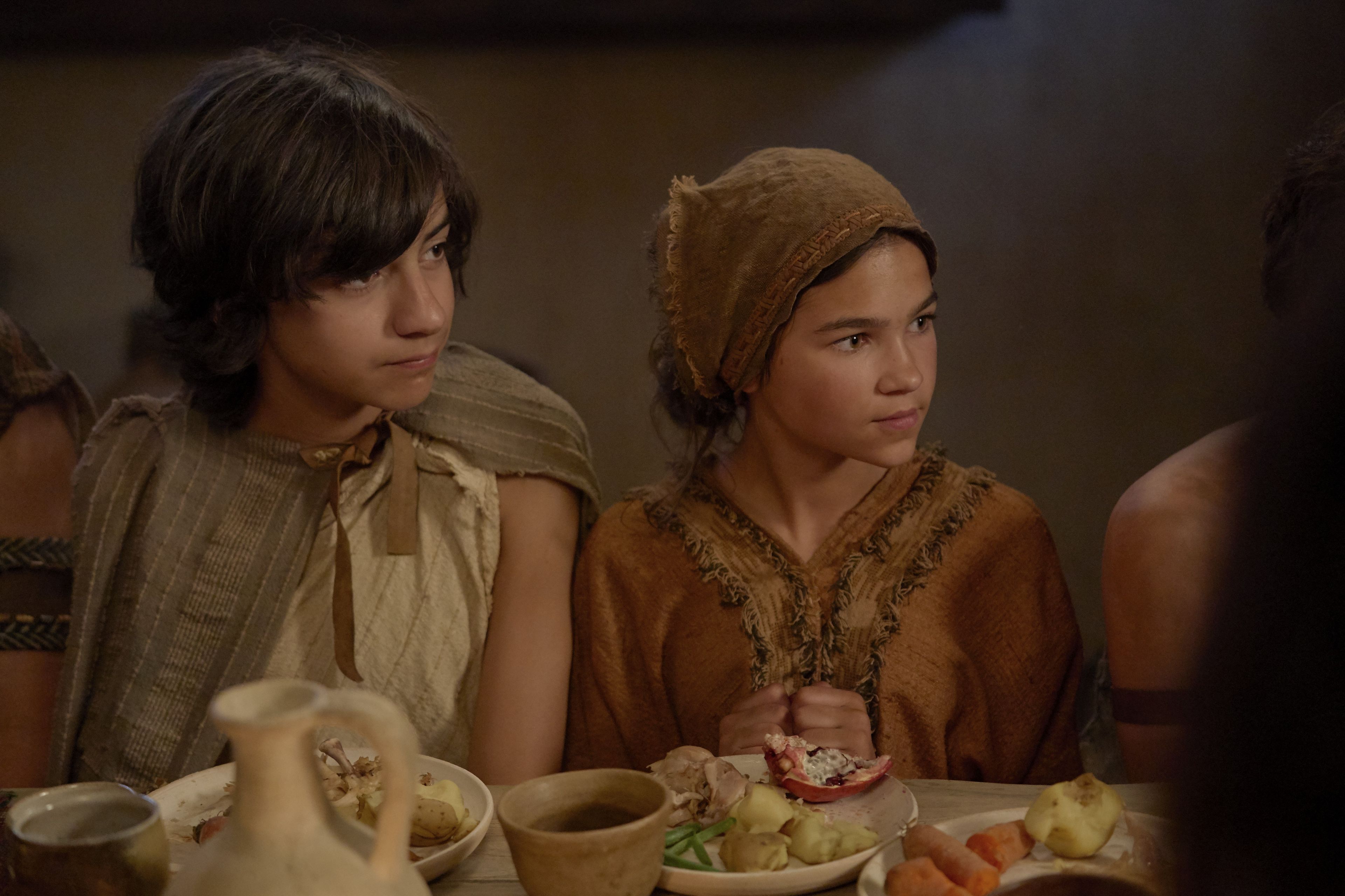 Jacob and other children sit around a table eating.