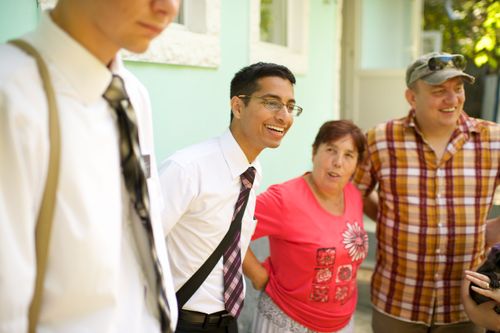 Two elder missionaries from Romania standing outside beside a woman with short hair and a man with a hat and a plaid shirt.