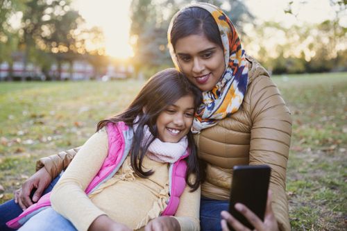 Muslim mother taking selfie with daughter in autumn park