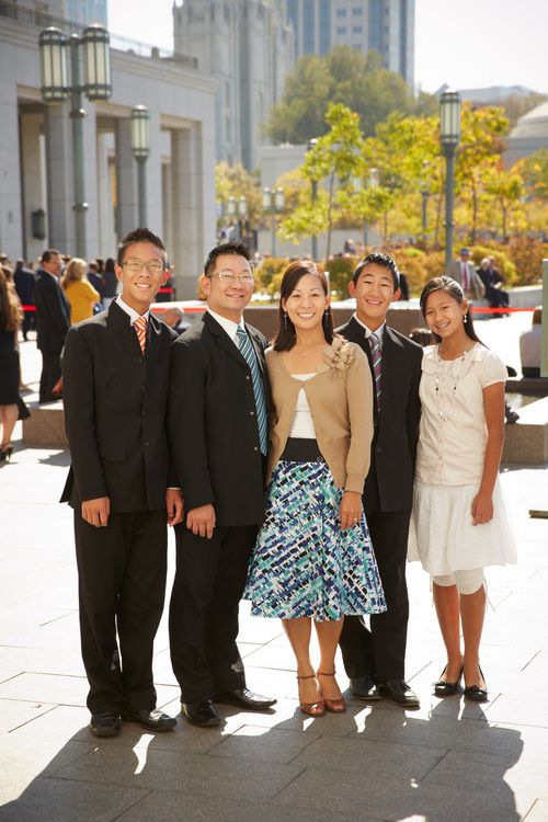 A father and mother stand beside their two sons in suits and their younger daughter while they wait outside the Conference Center.