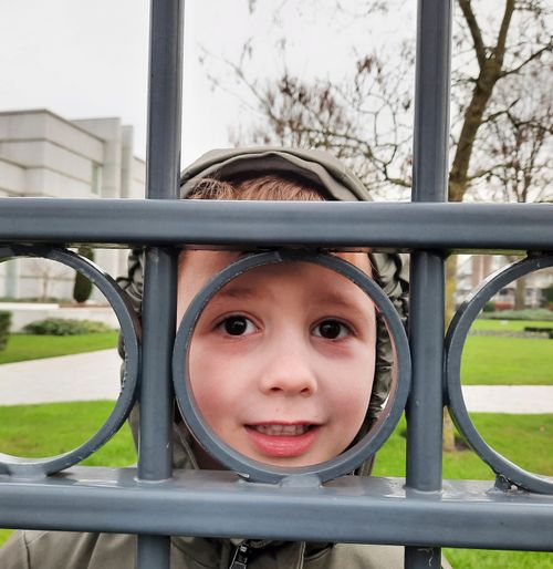 Boy looking through circle in fence at temple