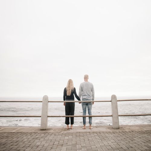 Couple holding hands looking into the ocean