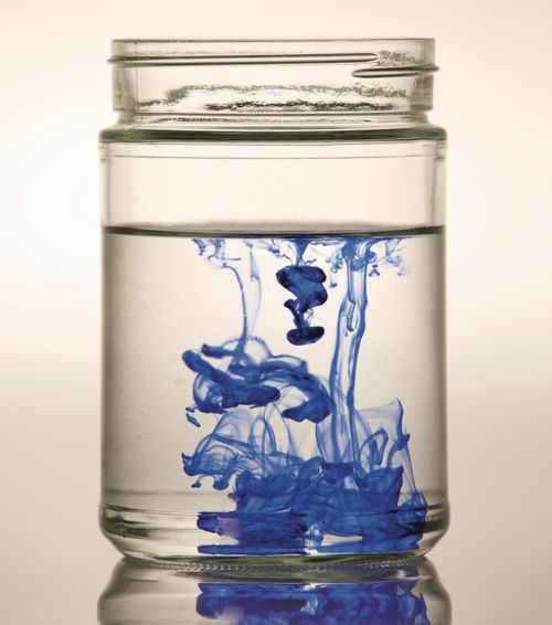 Blue ink spreading in a jar of water.