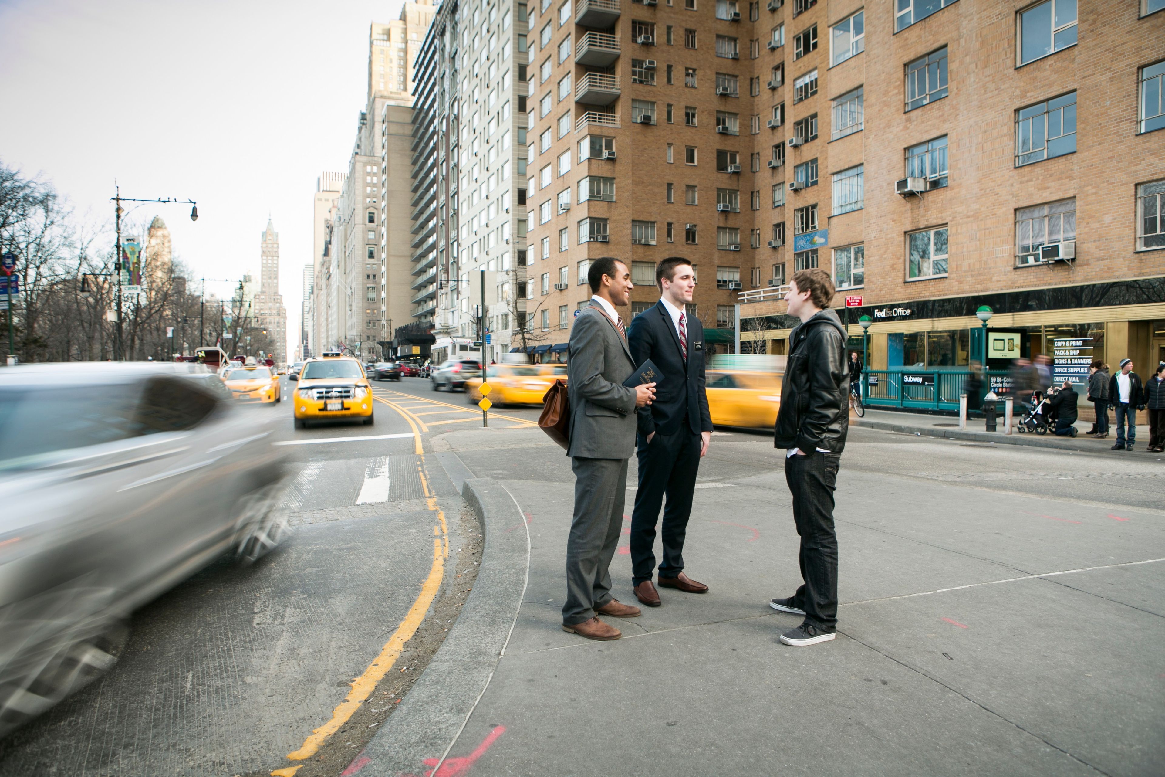 A young man talking to two elder missionaries in New York City.