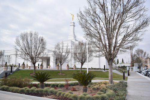 The Ciudad Juárez Mexico Temple with trees and other scenery, with clouds overhead.