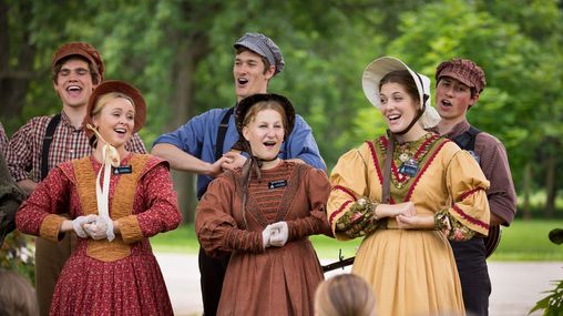 Young female and male missionaries singing songs while in pioneer clothing.  