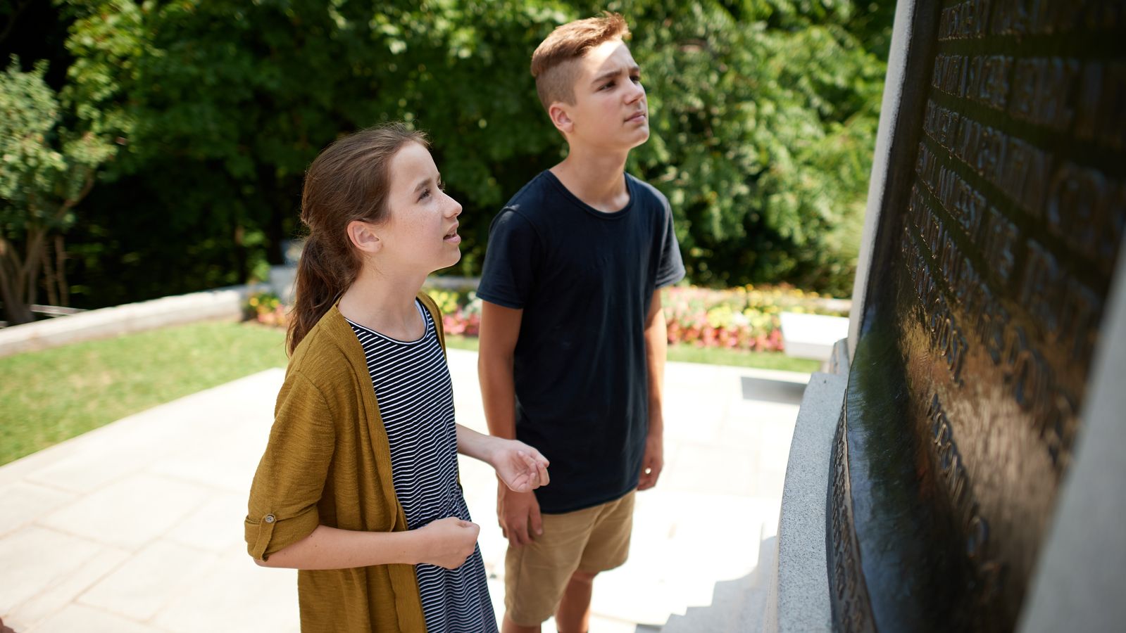 A large plinth/plaque with names is featured outside the visitors' center for the Hill Cumorah in Manchester, New York. 

Families look at the names.