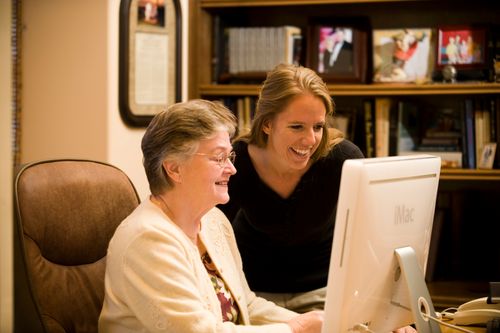 Two women working together on a computer in a home office.