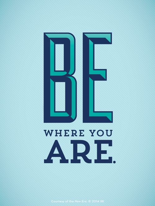 A solid light blue background with bold letters in different shades of blue: “Be where you are.”