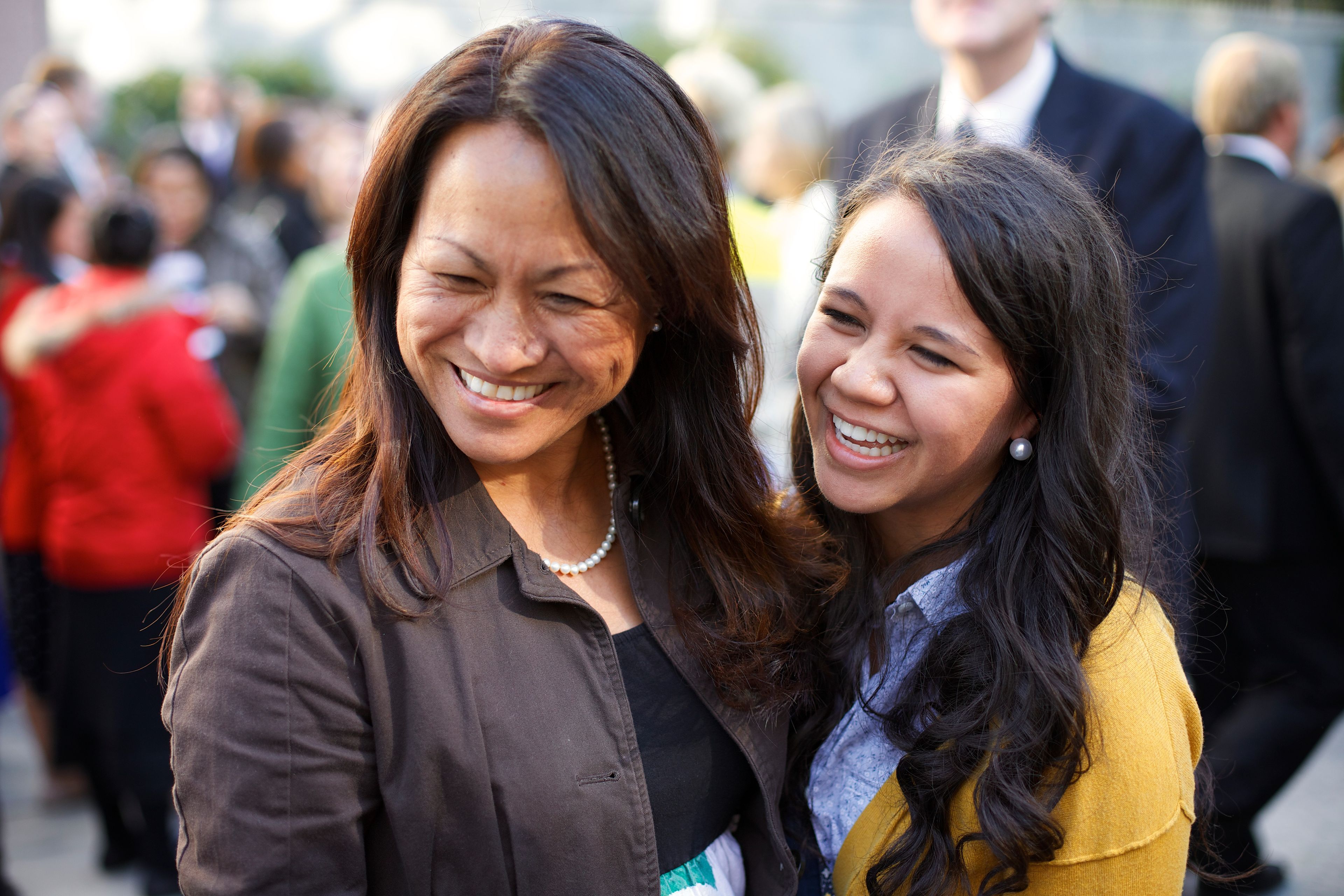 A woman standing and laughing with a young woman at general conference.  