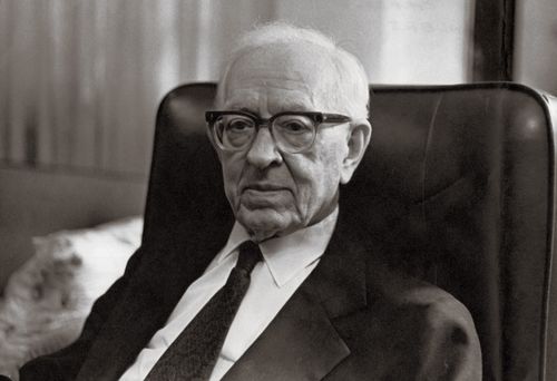 President Joseph Fielding Smith wearing a white shirt, a tie, a suit, and glasses, sitting in a black chair.