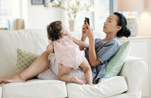 mother with cell phone while little daughter looks on