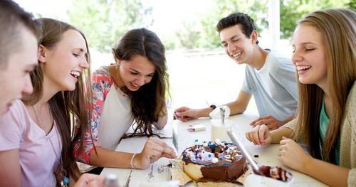 hombres y mujeres jóvenes decoran un pastel