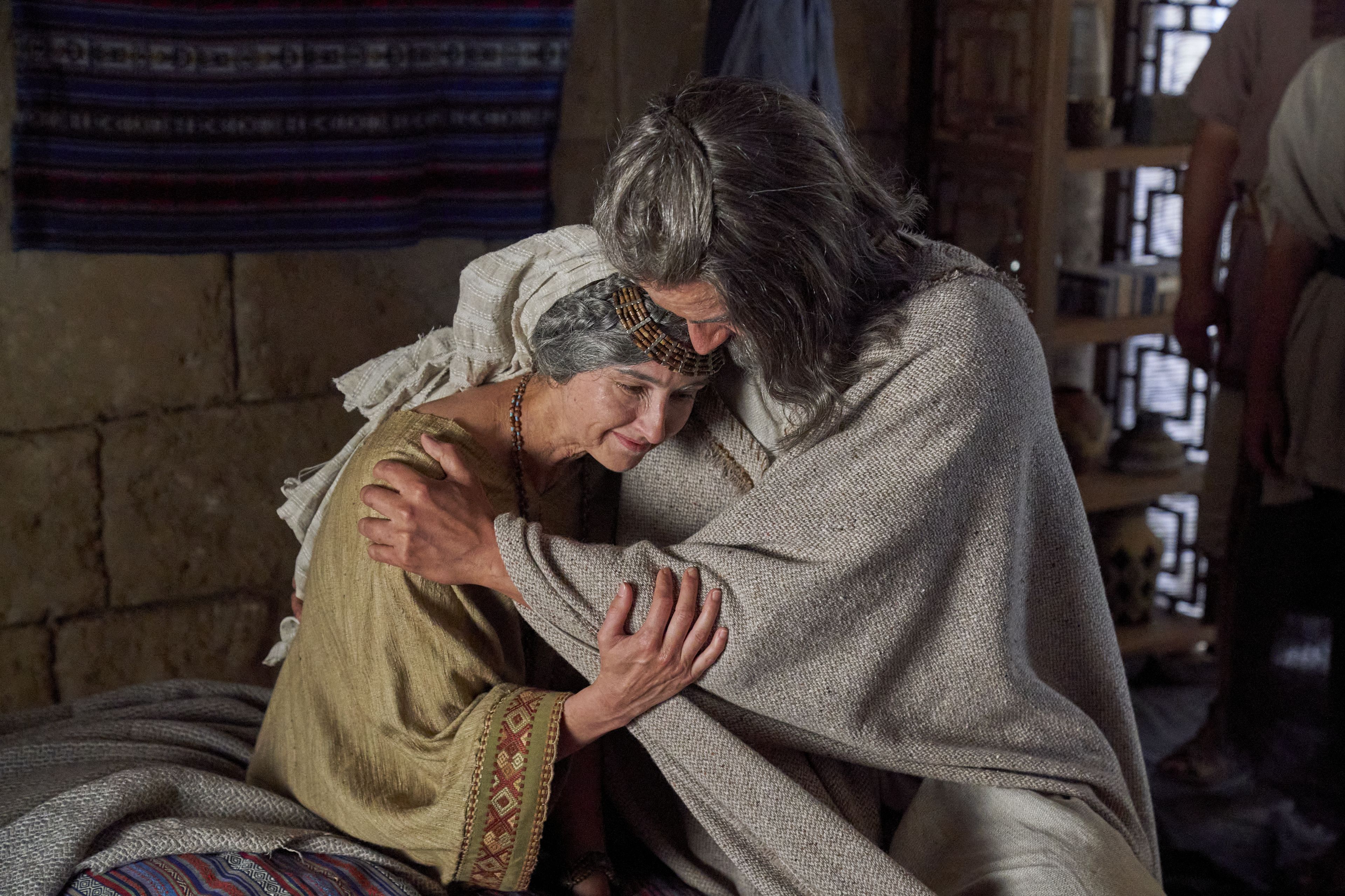 The wife of Alma the Elder and her husband embrace each other after learning of their son's conversion.