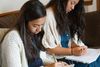 two youth writing in notebooks