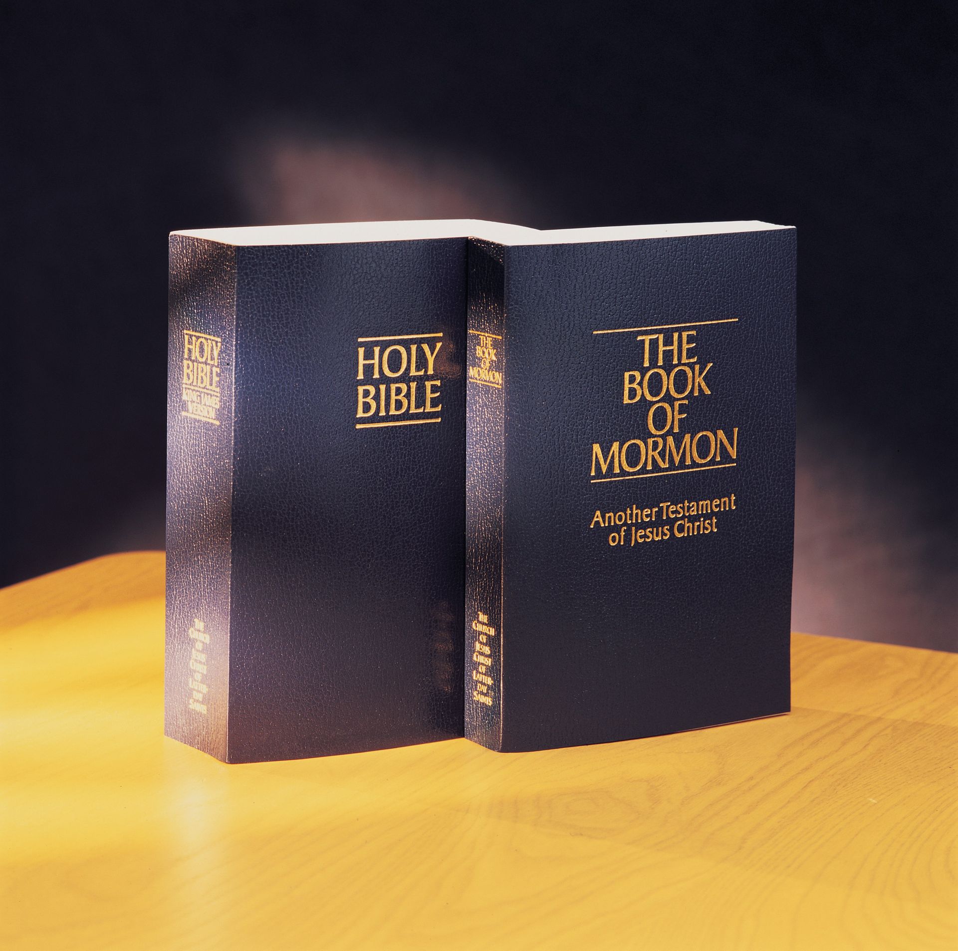A Bible and a Book of Mormon on a table.