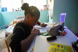 a young woman sitting in her bedroom and reading her scriptures