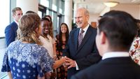 Worldwide Devotionals for Young Adults data-poster shots with Elder Nelson Shaking hands with young adults, laughing and smiling.