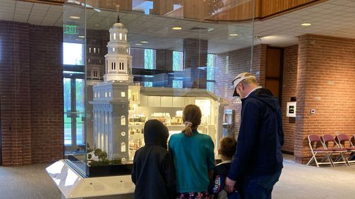 A family standing in front of a model of a large white temple.