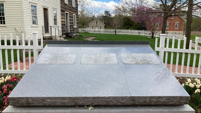 Large gray granite headstone tilted up at an angle.