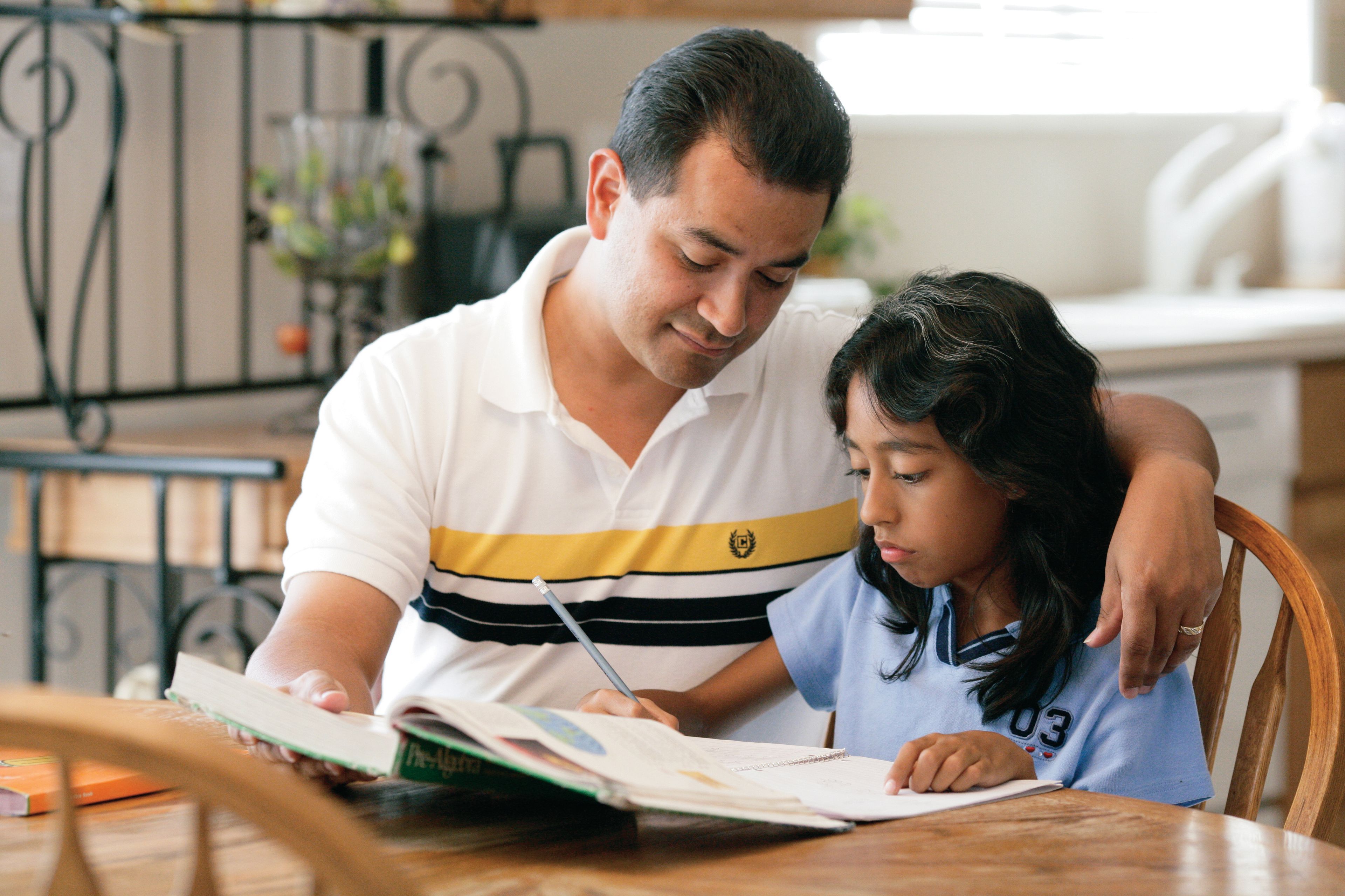 A father helps his daughter with her homework.