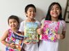 Three children holding copies of the Friend magazine