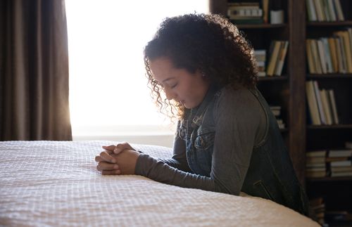 woman praying in bedroom