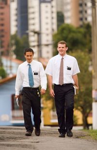 Two elder missionaries walking down a city sidewalk in Sao Paulo, Brazil.  There are buildings in the background.
