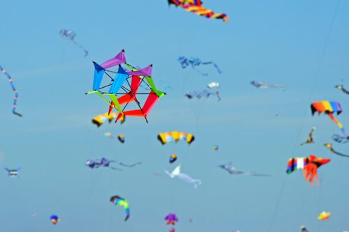 A group of colorful kites against a clear blue sky.