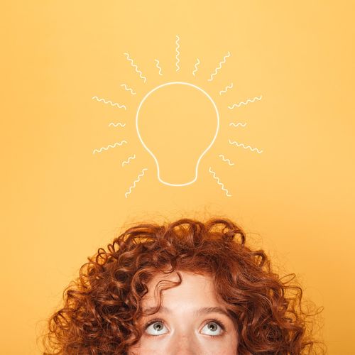 half face of young woman looking up at light bulb