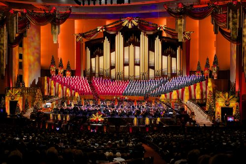 A view of the audience watching the Mormon Tabernacle Choir and orchestra, who are bordered by red curtains at the 2012 Christmas concert.