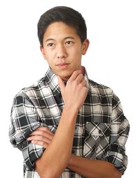 A young man in a black plaid shirt is resting his chin on his hand.