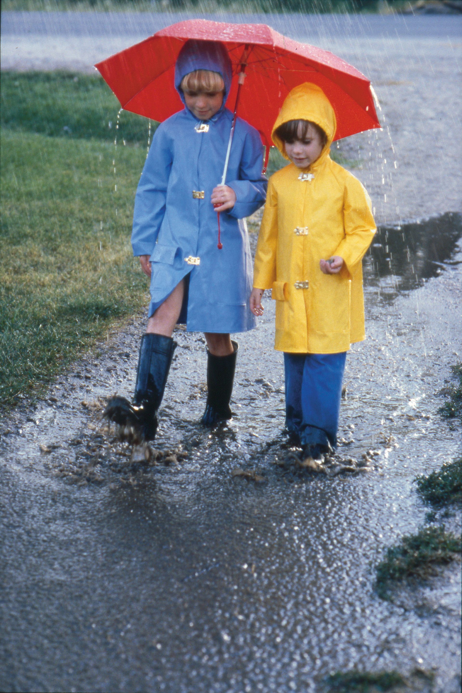 Two children playing together in the rain.