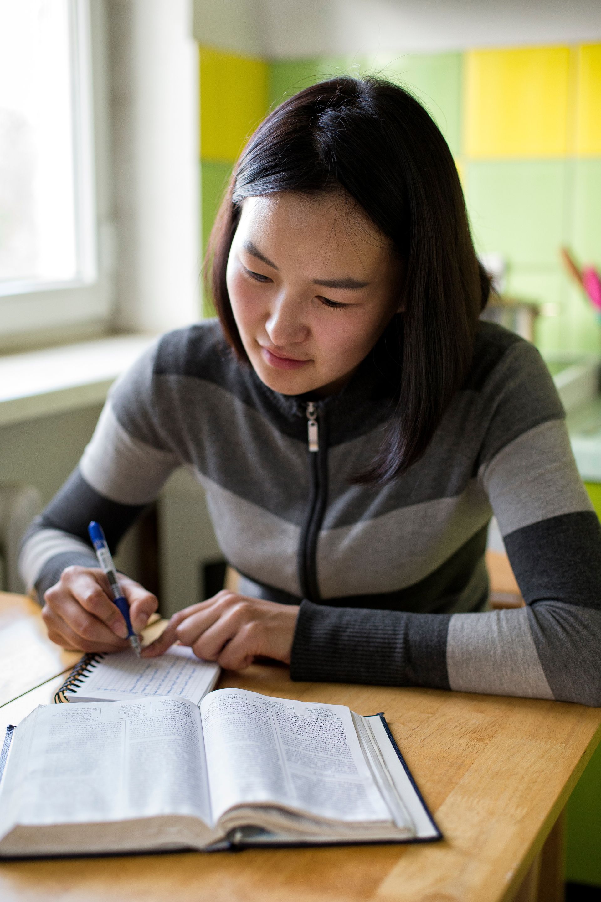 A woman takes notes as she studies her scriptures.