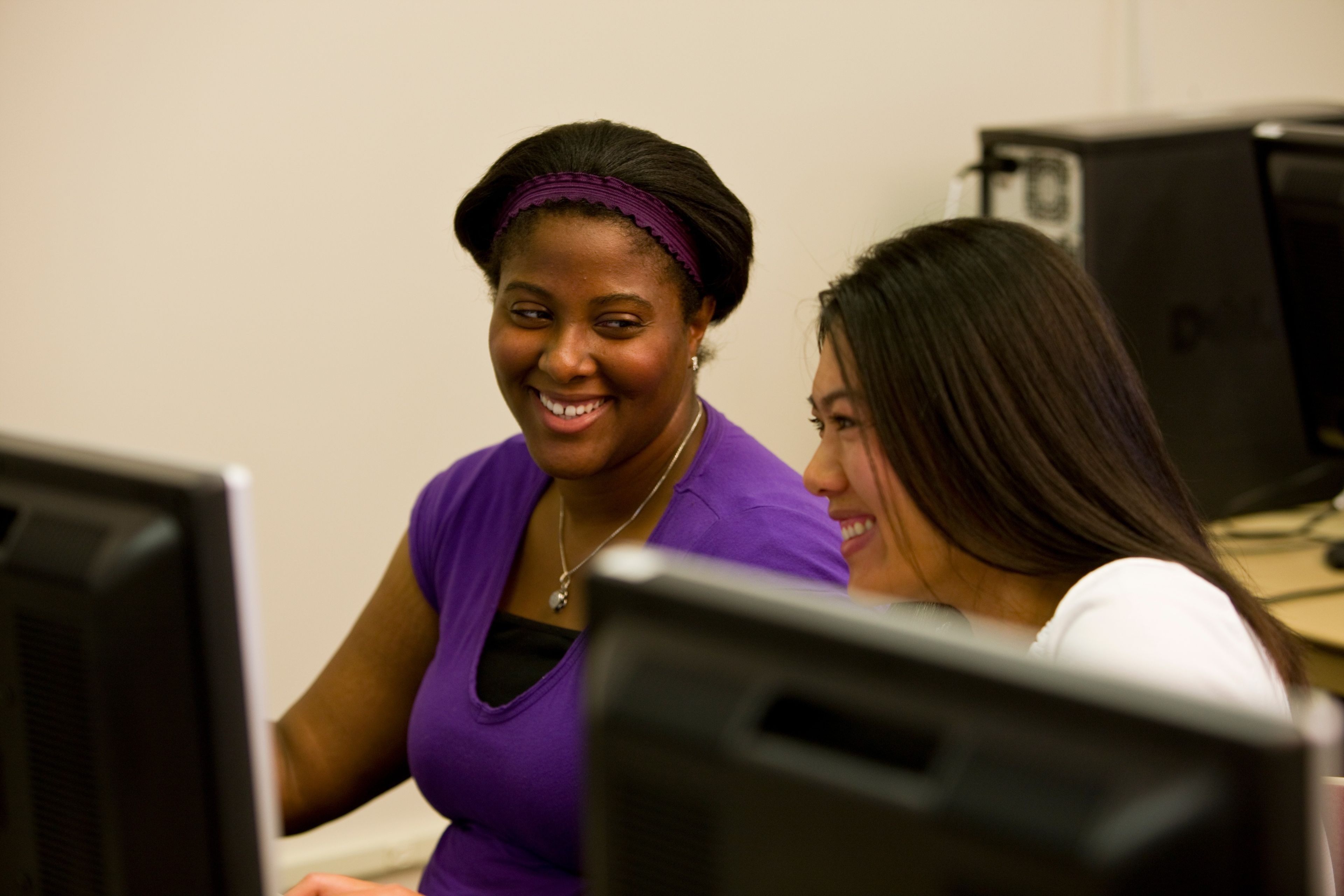 Two young women work together in a computer lab while doing family history research.  