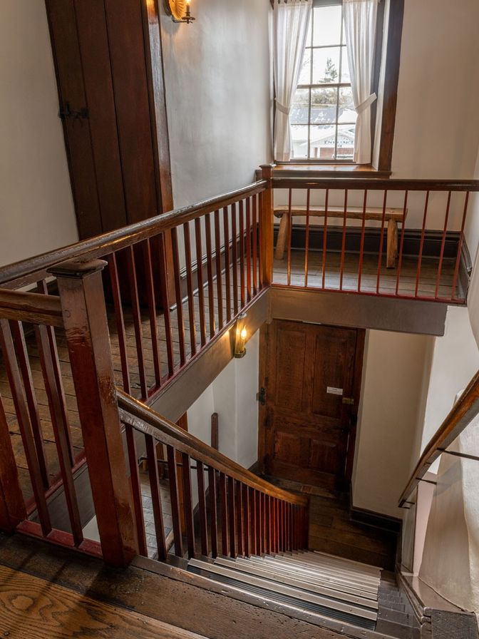 View from the top of the wooden stairs looking down at the front door of the building. 