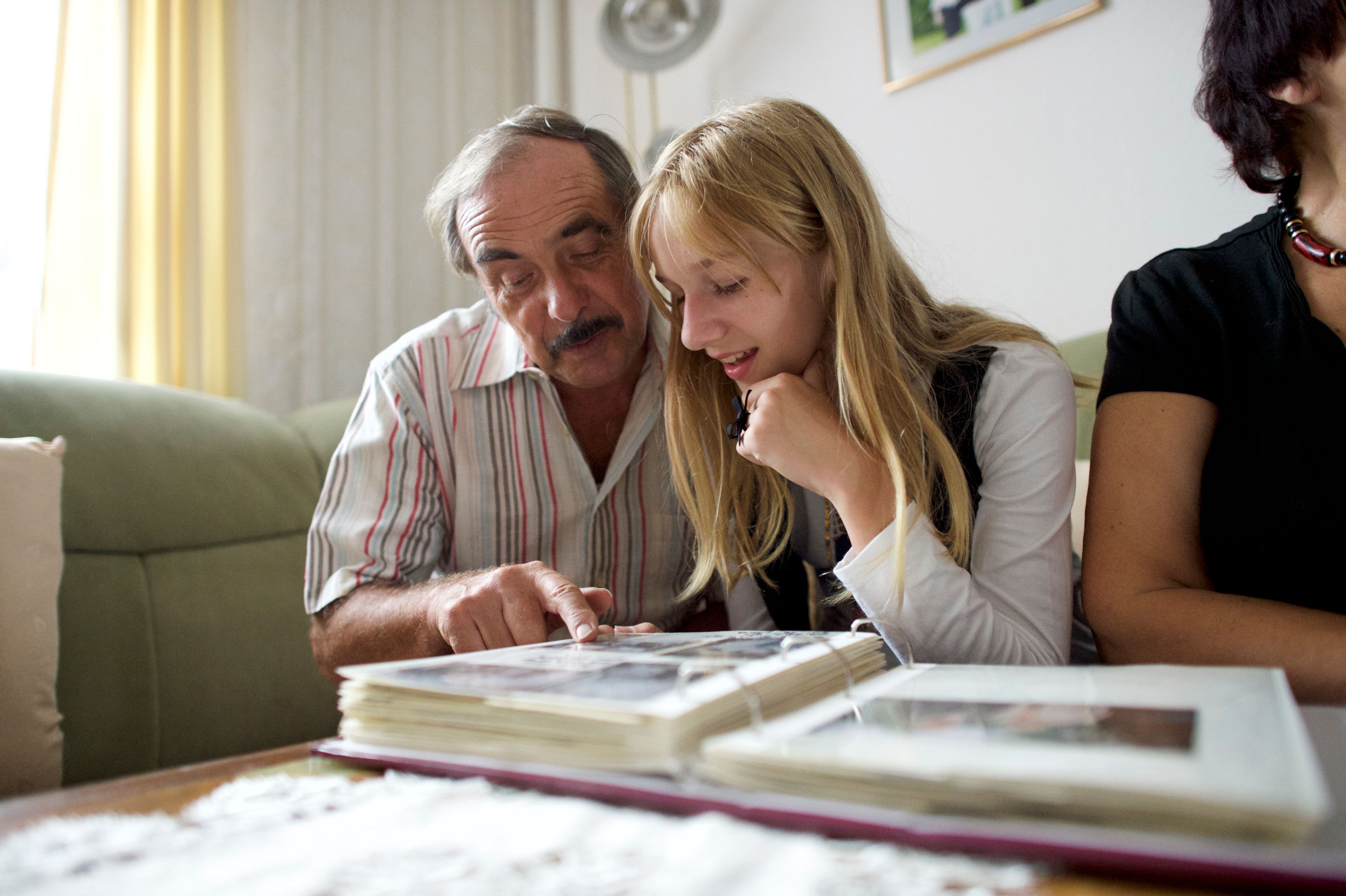 A man and his granddaughter look at a family photo album.