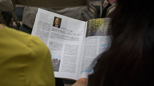 family reading general conference issue of magazine