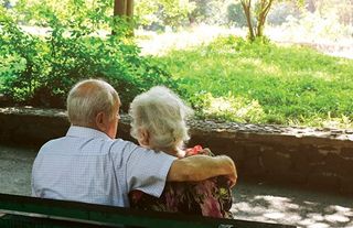 elderly couple sitting on a bench outside