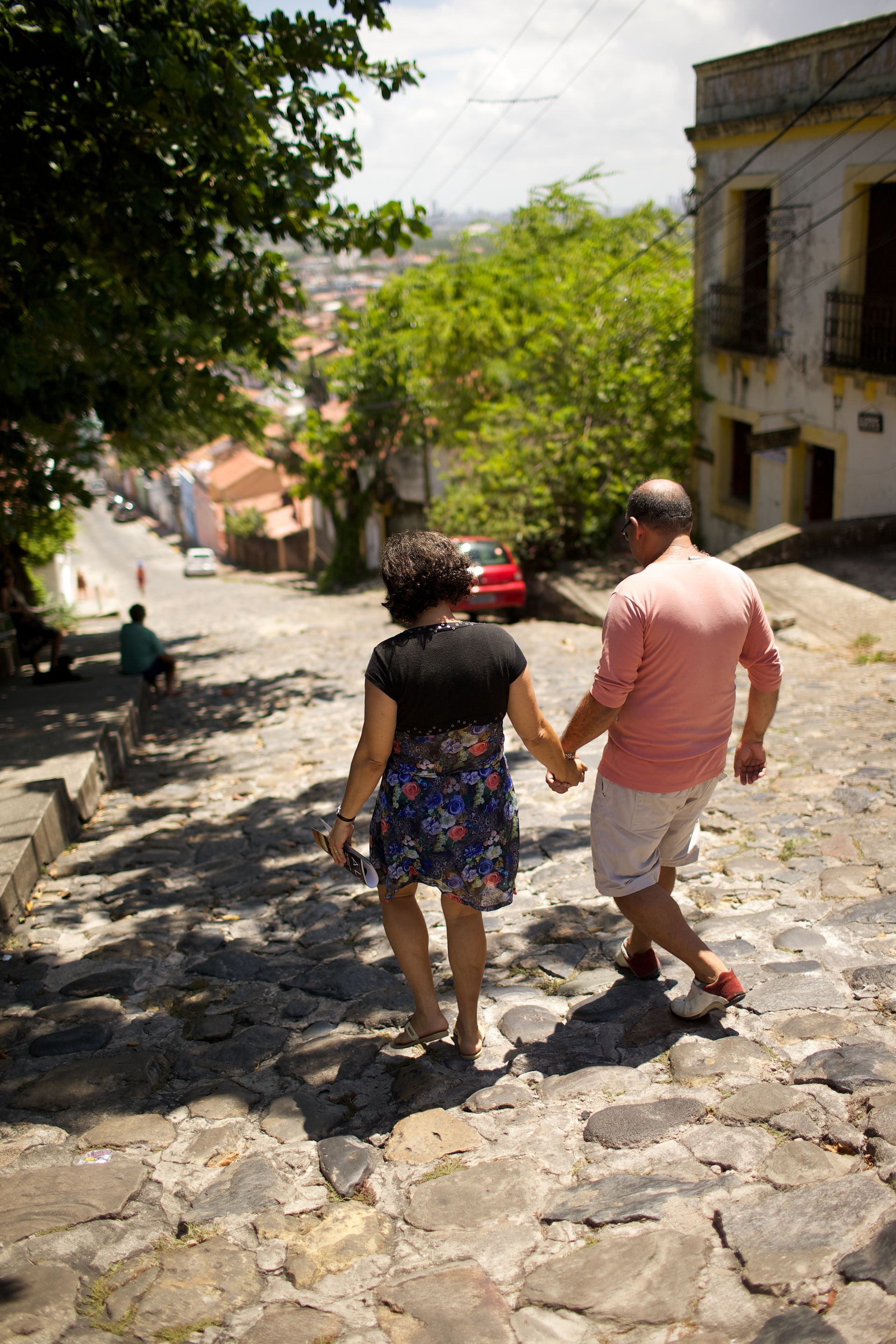 A couple holding hands and walking down a stone street in Brazil.  