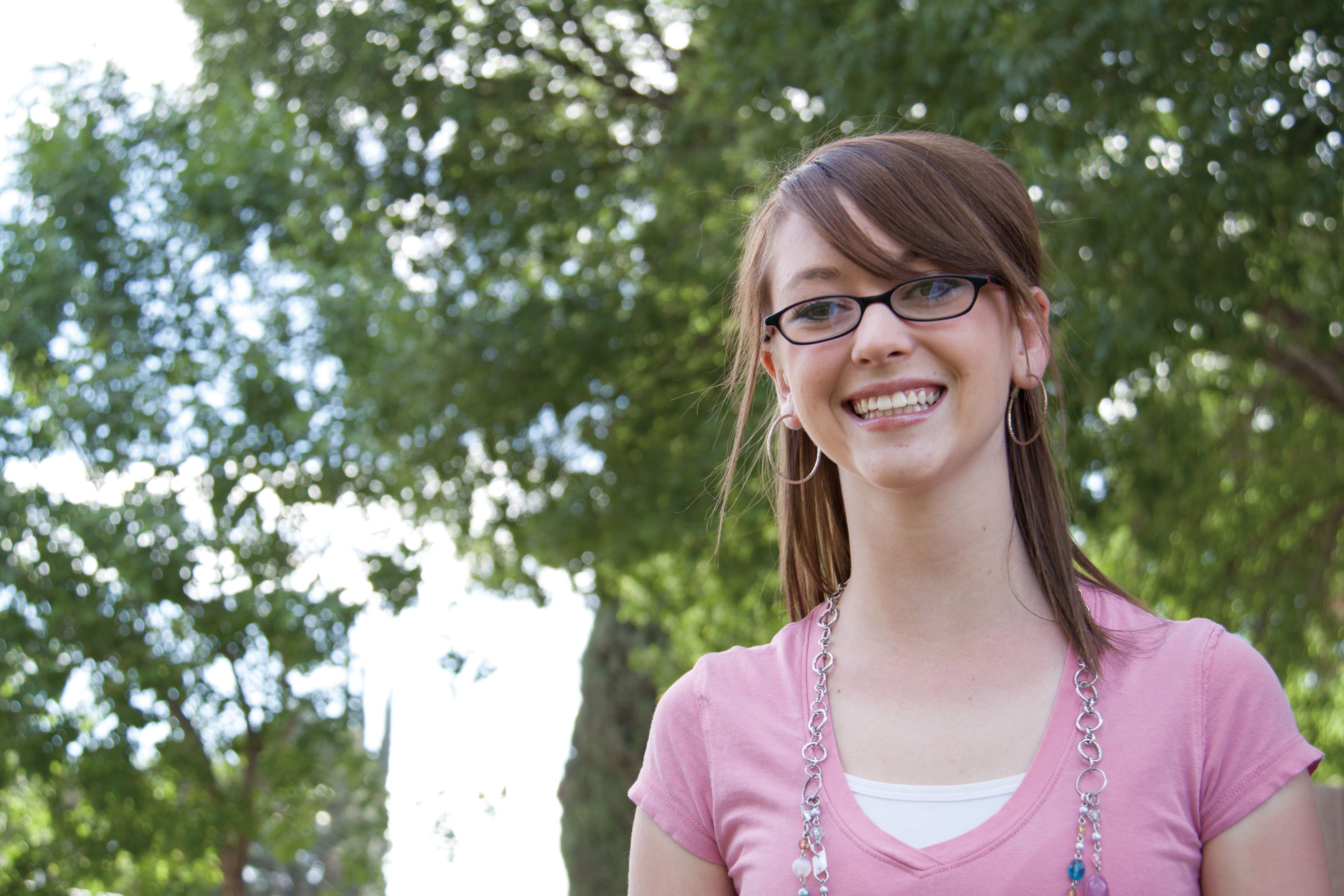 A portrait of a young woman with glasses, smiling.
