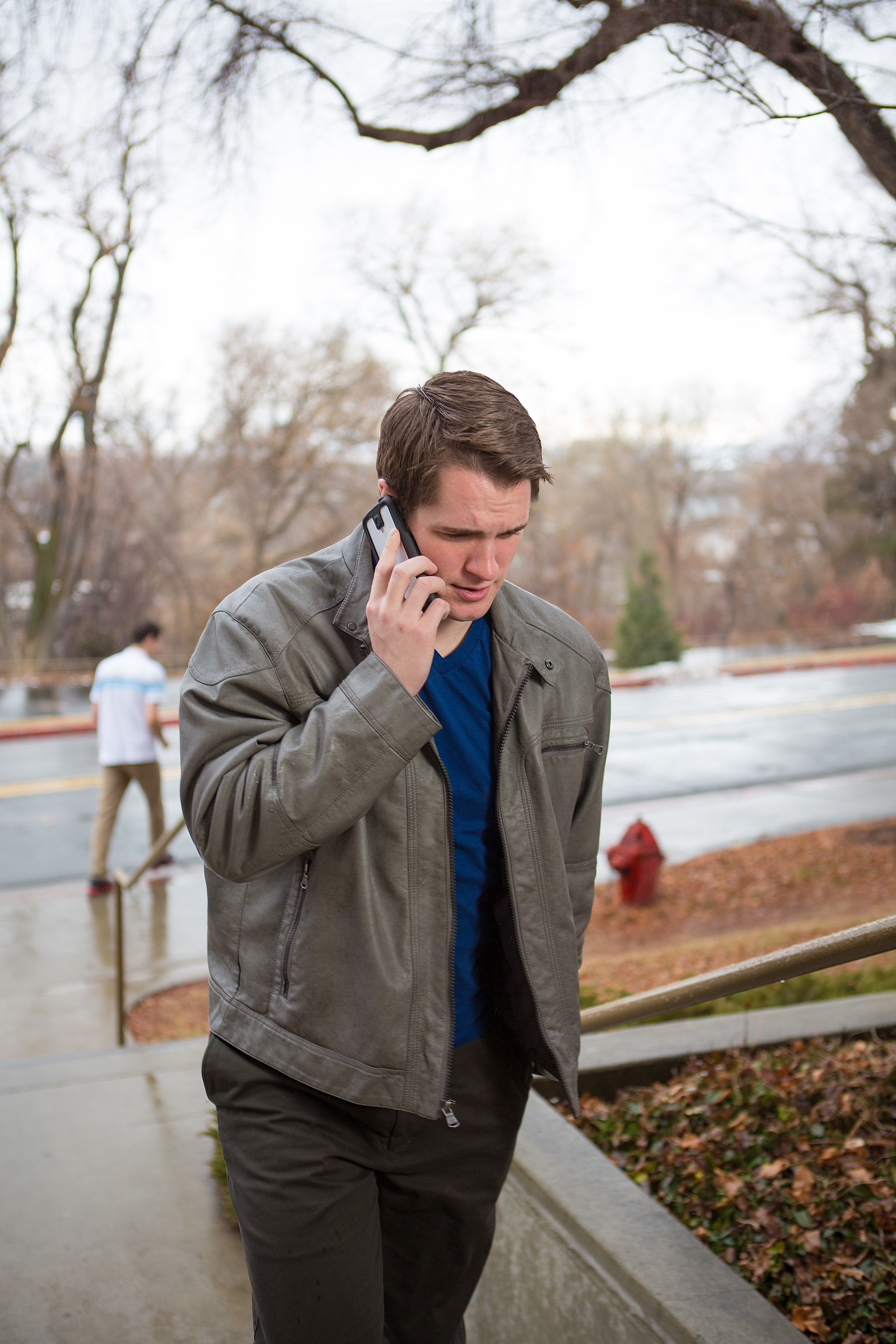 A young man walks outside while on the phone.