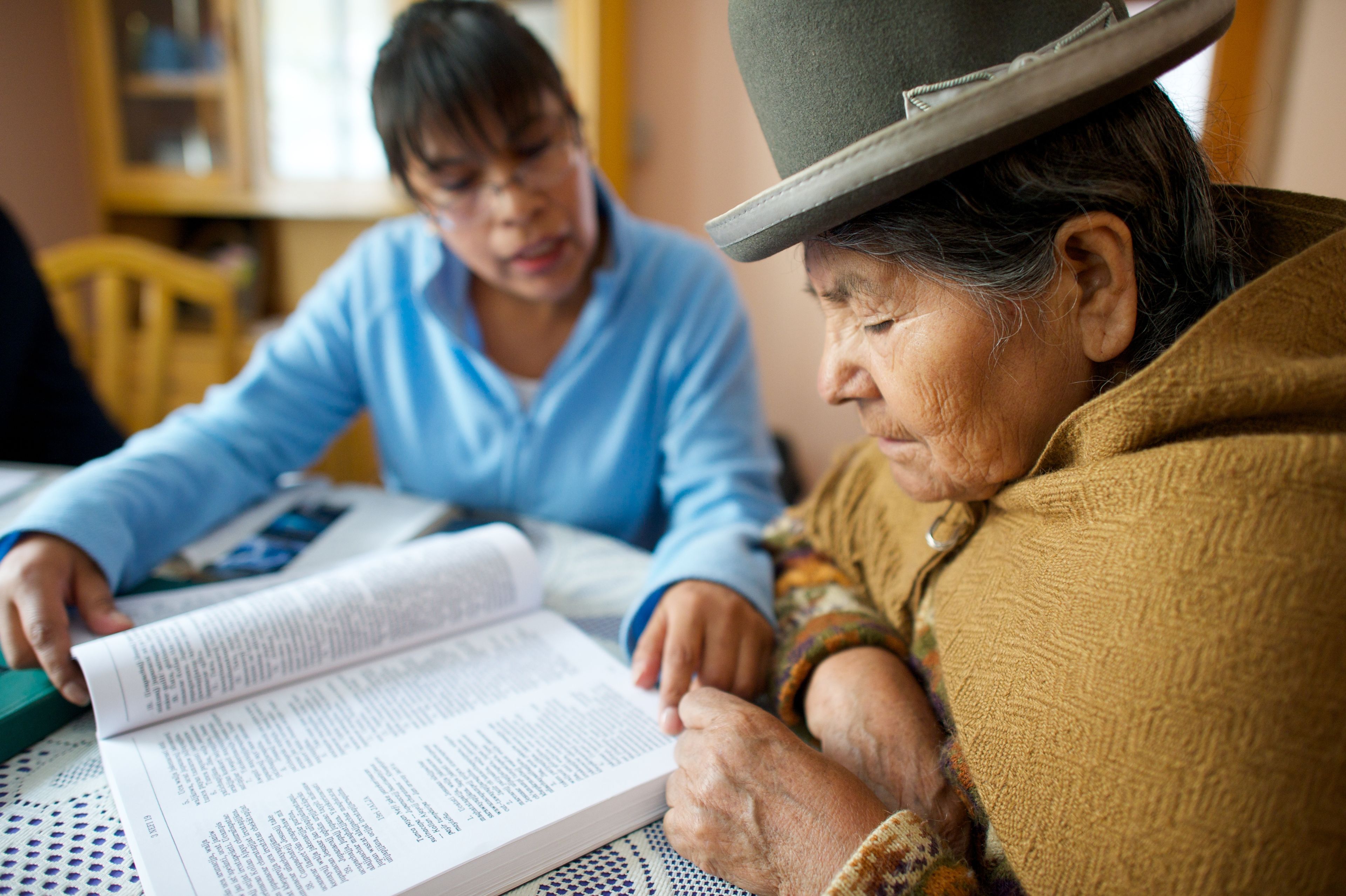 Two women from Bolivia sitting at a table and reading together.