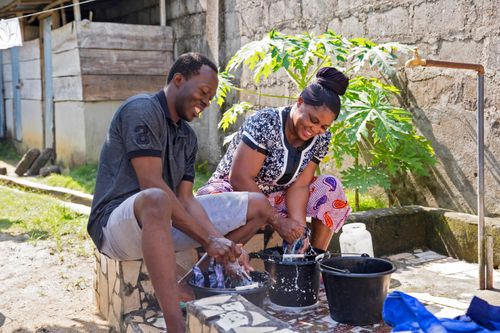 two people filling buckets from a well