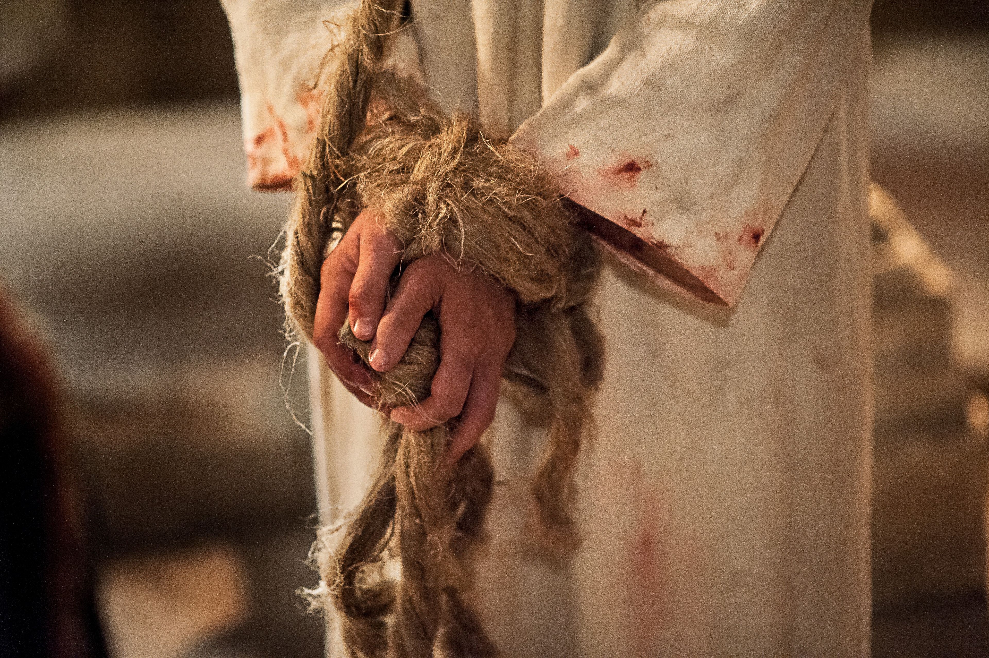 A detail of Christ’s hands bound by rope.