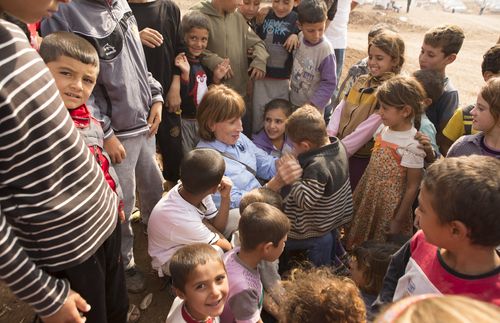 Aid worker surrounded by children in a refugee camp