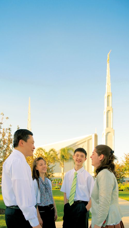 A family of four gathers and talks outside the Buenos Aires Argentina Temple on a sunny day.
