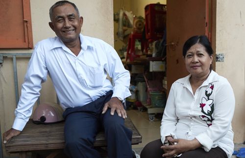 husband and wife sitting in front of house