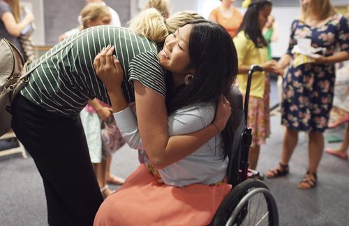 woman hugging a young woman in a wheelchair